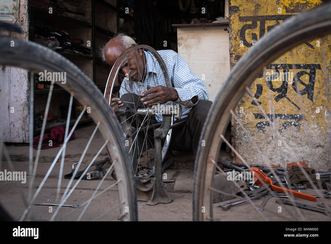 Un réparateur de vélos rayons de réglage à Varanasi, Inde. Banque D'Images