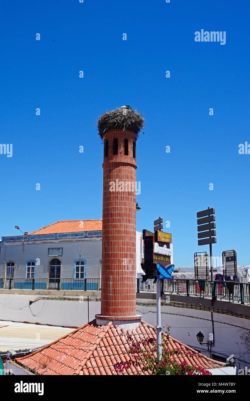 La nidification de la cigogne au sommet d'une cheminée en brique, Portimao, Algarve, Portugal, Europe. Banque D'Images