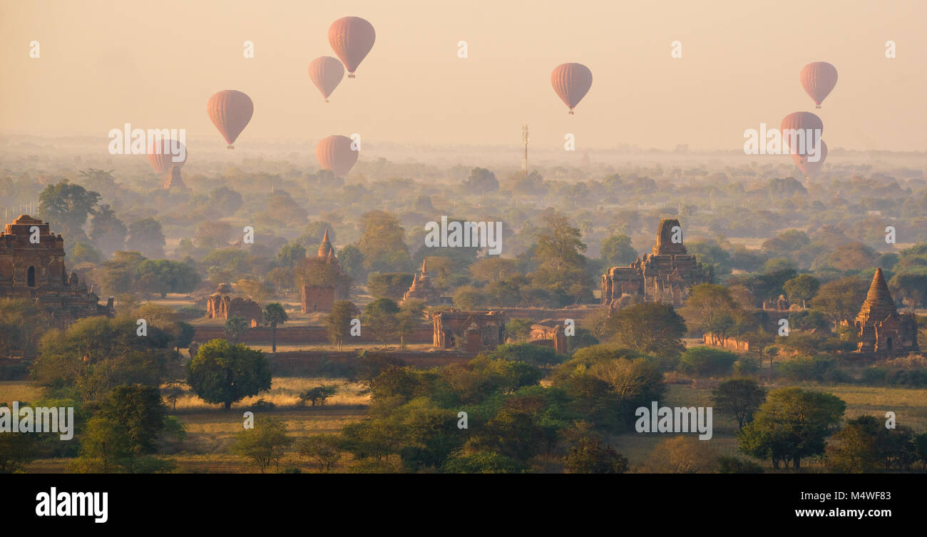 Lever du soleil voilé à Bagan, Myanmar, montgolfières sur l'horizon Banque D'Images