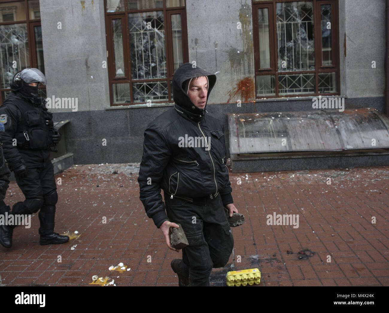 Kiev, Ukraine. Feb 18, 2018. Approche de la police un manifestant holding rocks essayer de briser les vitres de Rossotrudnichestvo office. Plusieurs dizaines de sympathisants et de membres de l'organisation radicale de droite de l'OUN ont défilé dans le centre de Kiev, passé plusieurs banques russes et Rossotrudnichestvo (Agence fédérale russe pour les compatriotes vivant à l'étranger et la coopération humanitaire internationale). Credit : Sergii Kharchenko/ZUMA/Alamy Fil Live News Banque D'Images