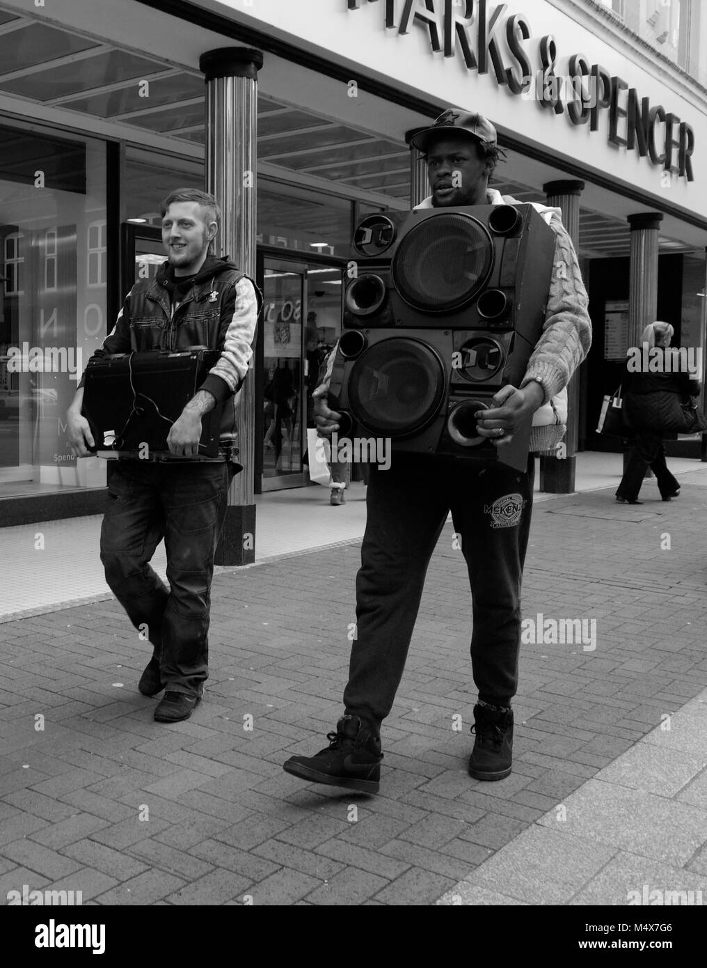 Photographie noir et blanc de deux hommes marcher avec des chaînes hi-fi, à Kingston, Surrey, England, UK London Crédit : Snapper Banque D'Images