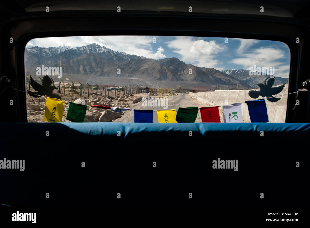 Les drapeaux de prières bouddhistes accrocher dans la fenêtre arrière d'un véhicule à Leh, Ladakh. Banque D'Images