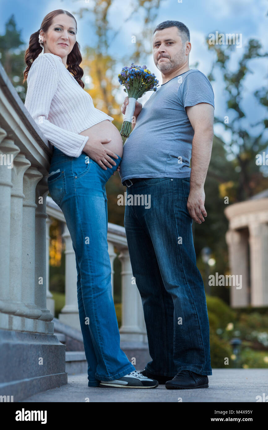 Jeune homme avec une femme enceinte. Ils se tiennent avec leurs estomacs les uns contre les autres Banque D'Images