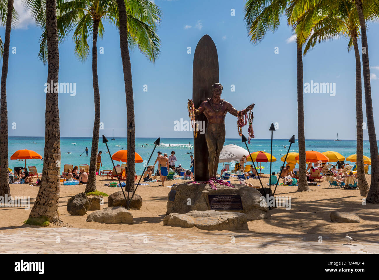 La statue de Duke Kahanamoku, surfeur hawaïen et Olympien, sur la plage de Waikiki avec le soleil, les surfeurs, les touristes, parasols de plage à Honolulu, Hawaii, USA. Banque D'Images