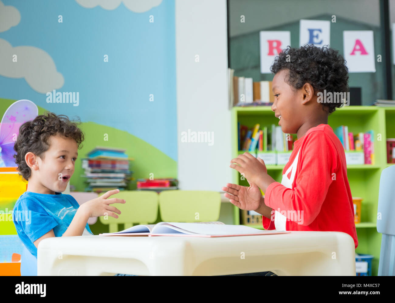 Deux garçon enfant s'asseoir sur une table et le coloriage de livre dans la bibliothèque de l'école maternelle préscolaire,concept éducatif. Banque D'Images