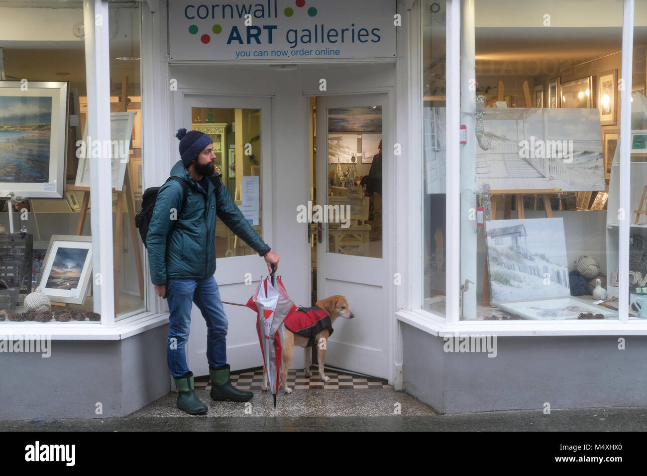 Un homme et son chien à l'abri de la pluie. Banque D'Images