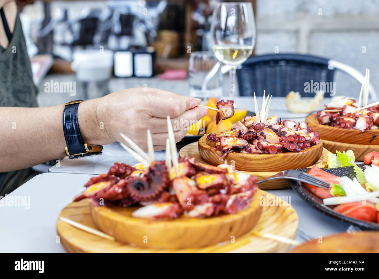 Les personnes mangeant Pulpo a la gallega avec pommes de terre. Poulpe galicien plats. Plats célèbres de la Galice, Espagne. Banque D'Images