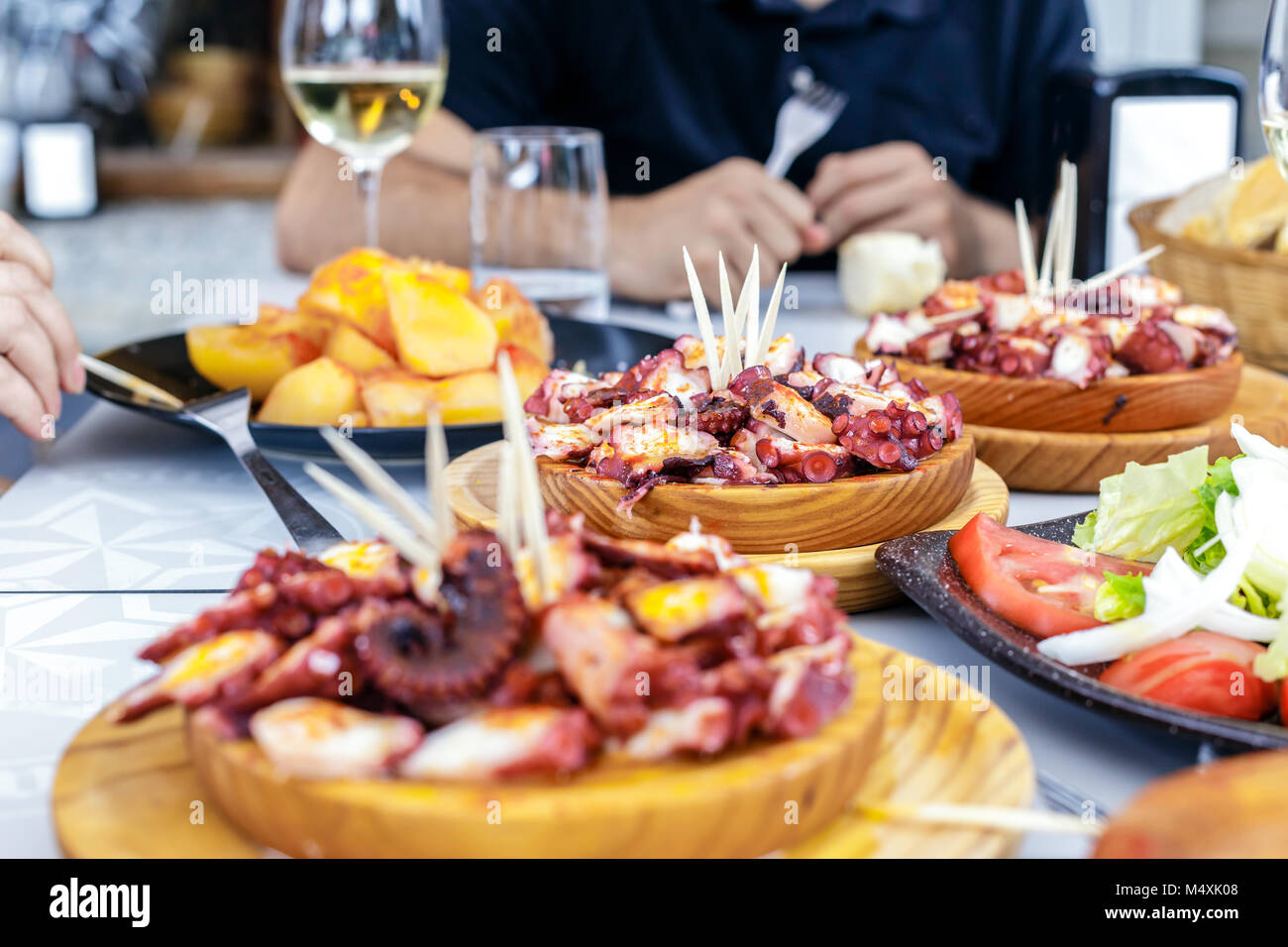 Les personnes mangeant Pulpo a la gallega avec pommes de terre. Poulpe galicien plats. Plats célèbres de la Galice, Espagne. Banque D'Images
