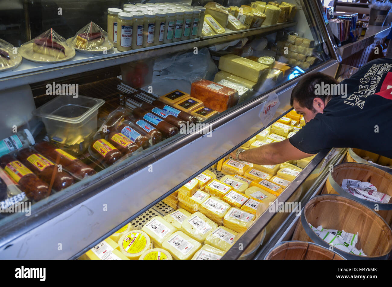 Homme atteint dans une armoire frigorifique rempli de fromage primé à Baumgartner à Monroe, WI. Banque D'Images