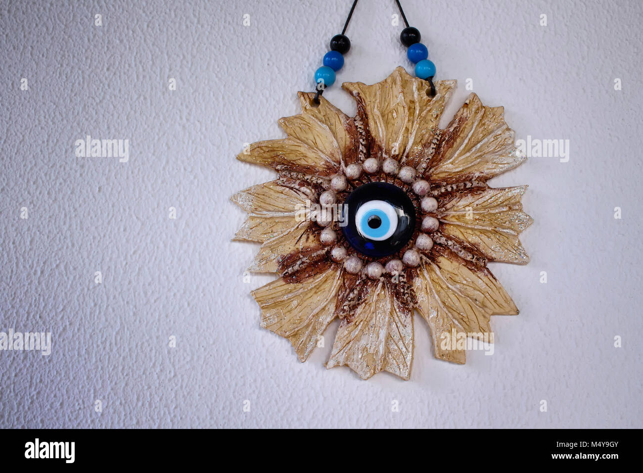Bleu mur objet décoratif, en forme de fleur et faites avec oeil mauvais. C'est sur fond de plâtre blanc. Banque D'Images