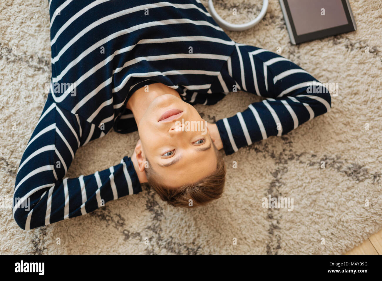 Adolescent sérieux se trouvant sur le plancher et la pensée Banque D'Images