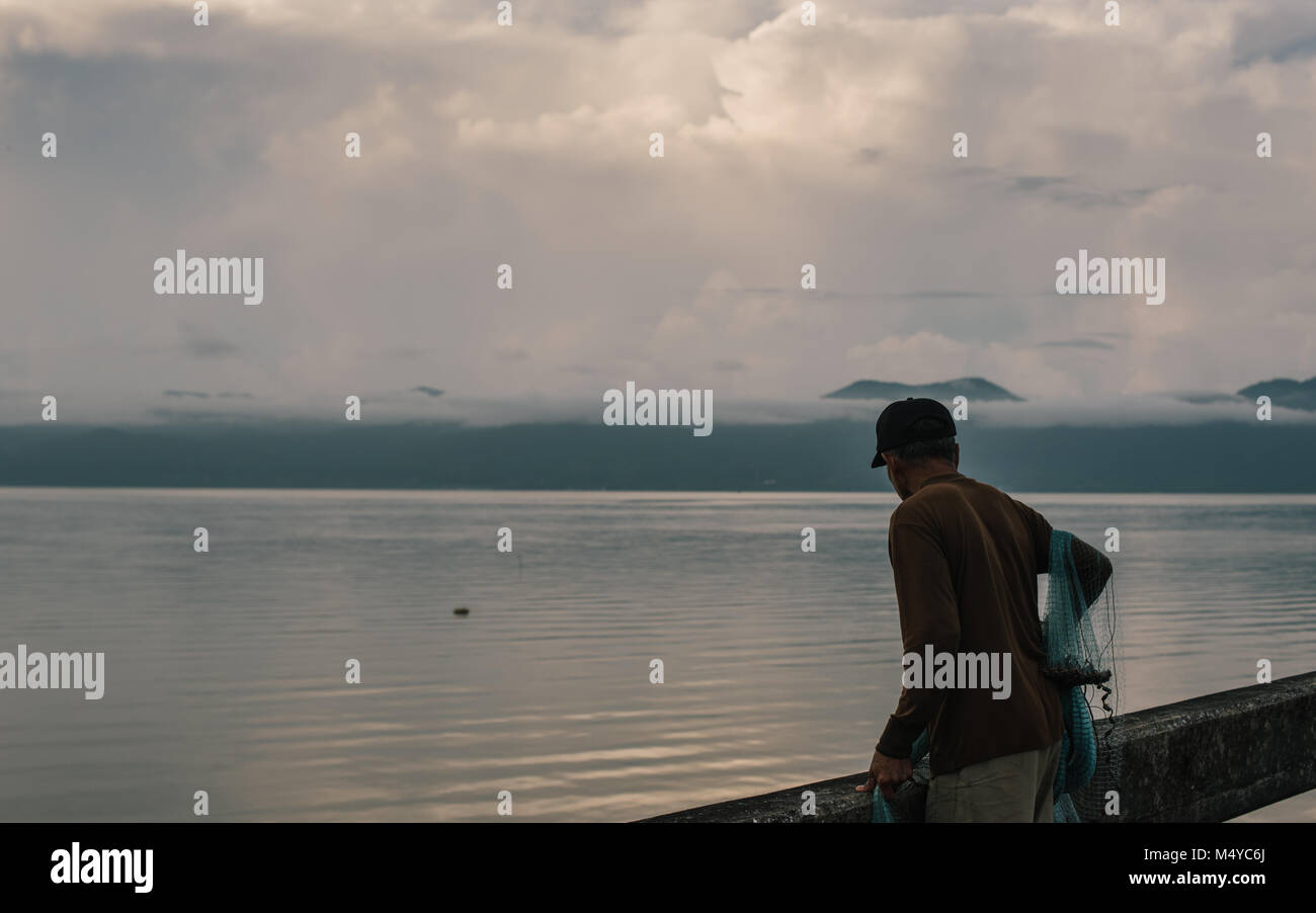 Old man Looks pour le poisson avec son filet dans Trat sur la côte de la Thaïlande, près d'îles, Koh Mak, Koh Chang et Koh Kut Banque D'Images