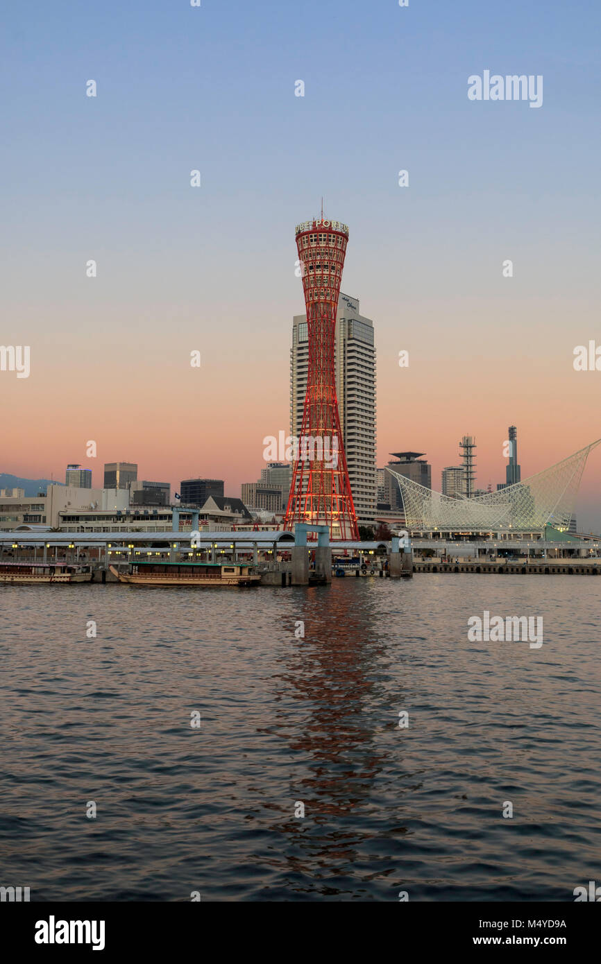 Le Japon, Kobe. Kobe port Tower, rouge avec l'Okura Hotel derrière, et le musée maritime sur le front de mer. Le crépuscule juste après le coucher du soleil, ciel orange au bleu. Banque D'Images