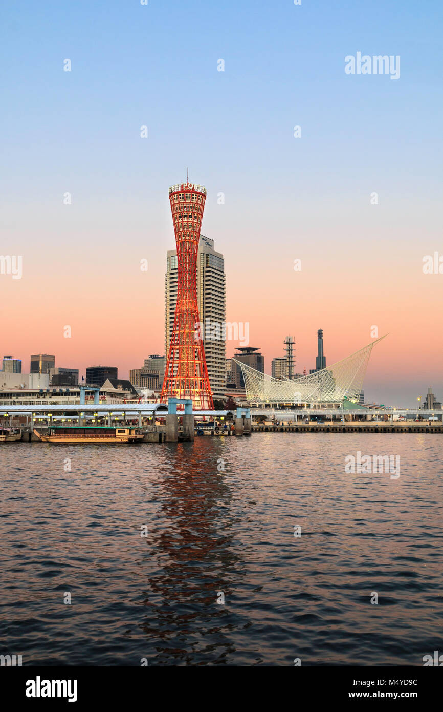 Le Japon, Kobe. Kobe port Tower, rouge avec l'Okura Hotel derrière, et le musée maritime sur le front de mer. Le crépuscule juste après le coucher du soleil, ciel orange au bleu. Banque D'Images