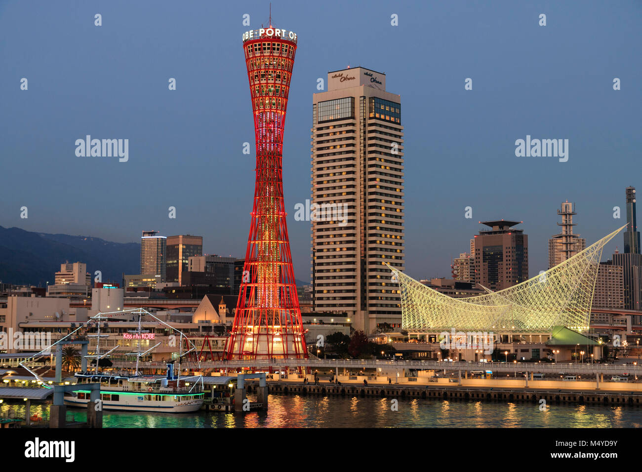 Le Japon, Kobe. Kobe port Tower, rouge avec l'Okura Hotel derrière, et le musée maritime. La nuit, crépuscule période. Banque D'Images