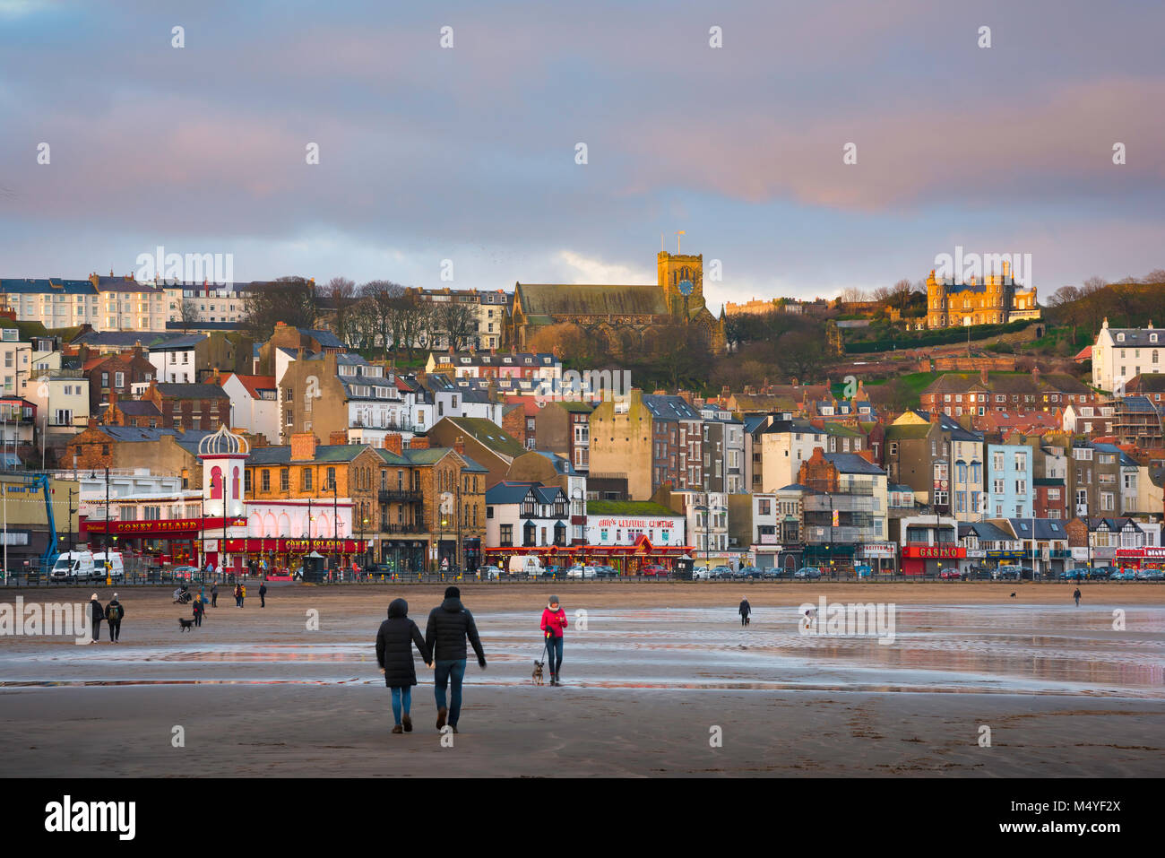 Scarborough Yorkshire, vue hors saison des personnes marchant au coucher du soleil sur South Bay Beach à Scarborough, North Yorkshire, Angleterre, Royaume-Uni Banque D'Images