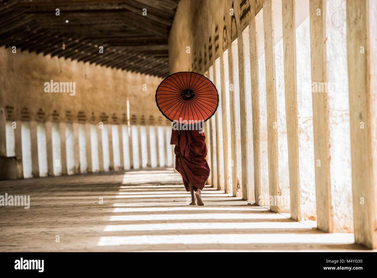Moine aux costumes traditionnels rouges et parapluie rouge dans le temple géant bouddhiste Banque D'Images