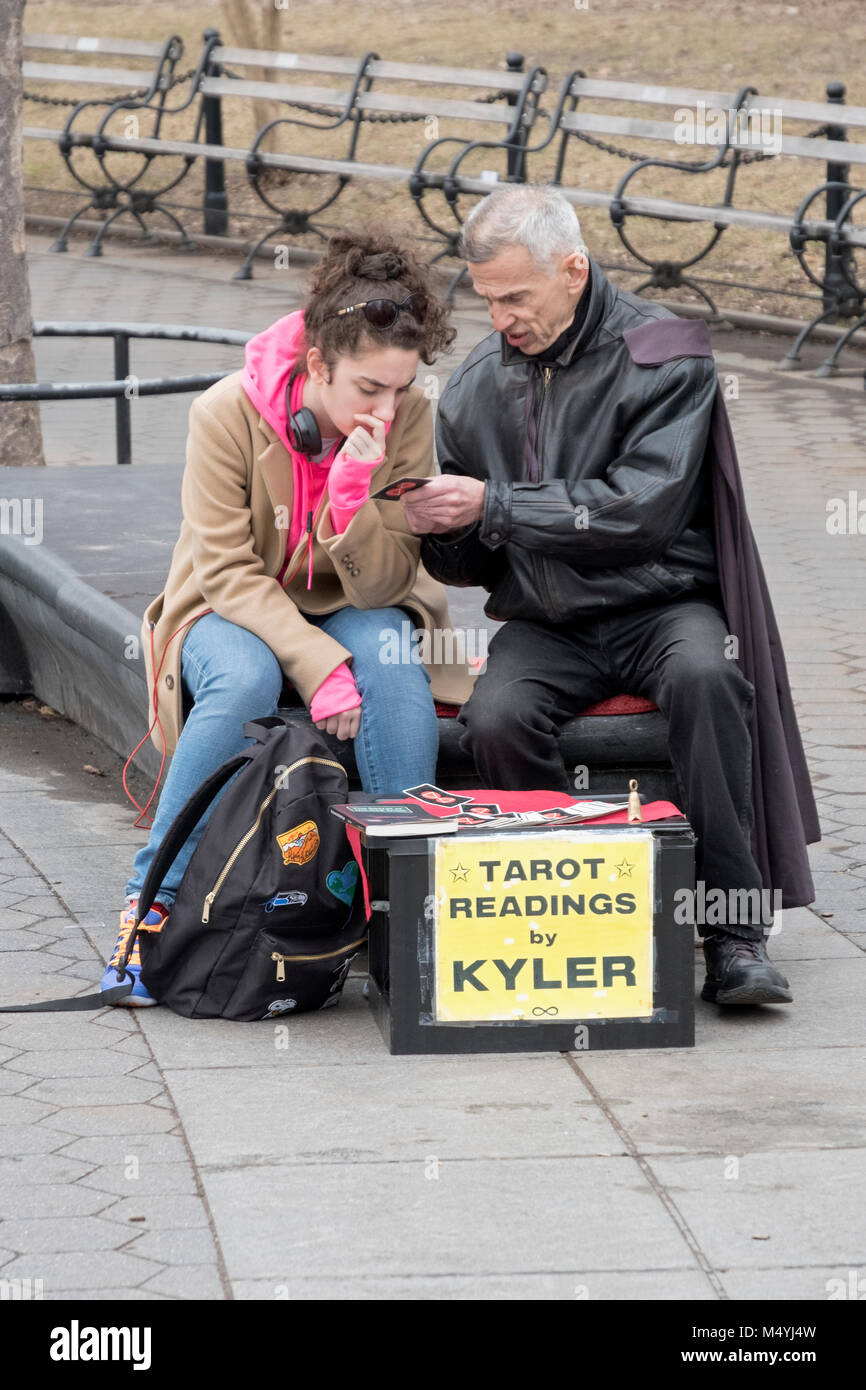Kyler le psychique n'est une lecture de carte de tarot pour une jeune femme intéressée dans Washingotn Square Park à Manhattan, New York City. Banque D'Images