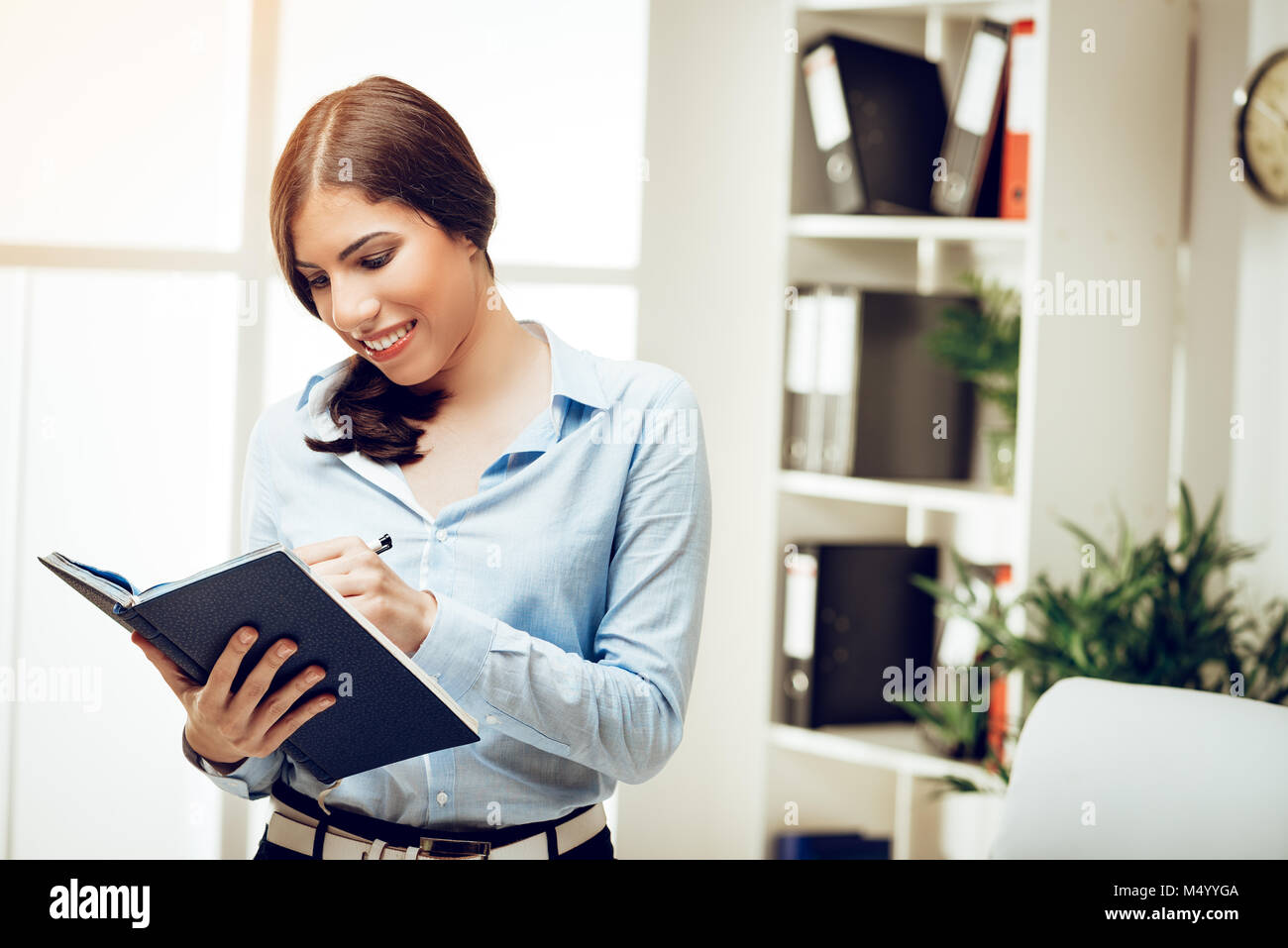 Belle Jeune femme debout avec succès à l'office et de l'écriture en charpente avec sourire sur son visage. Banque D'Images