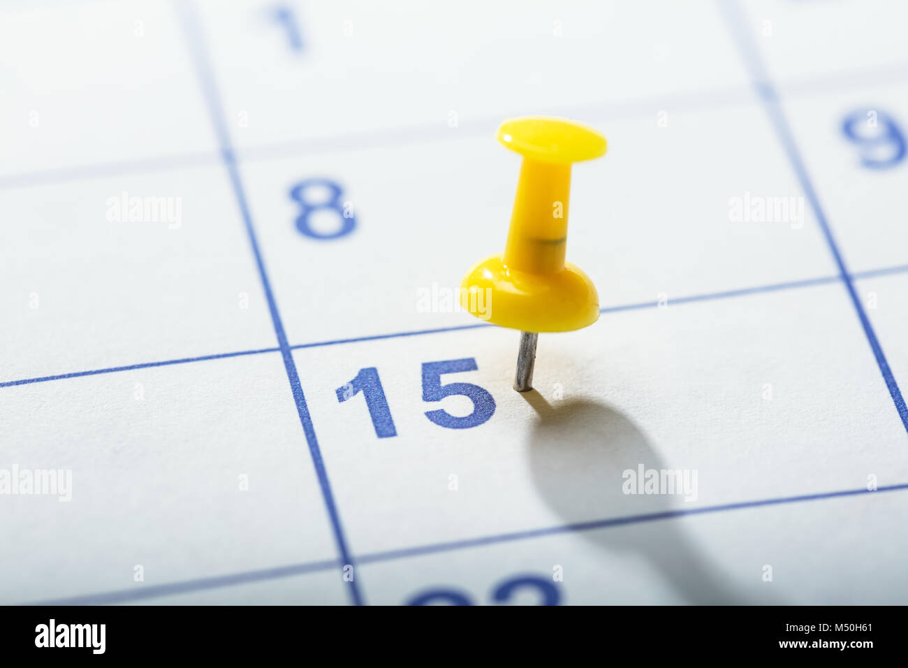 Close-up de punaise jaune collé sur la date dans le calendrier 15e Banque D'Images