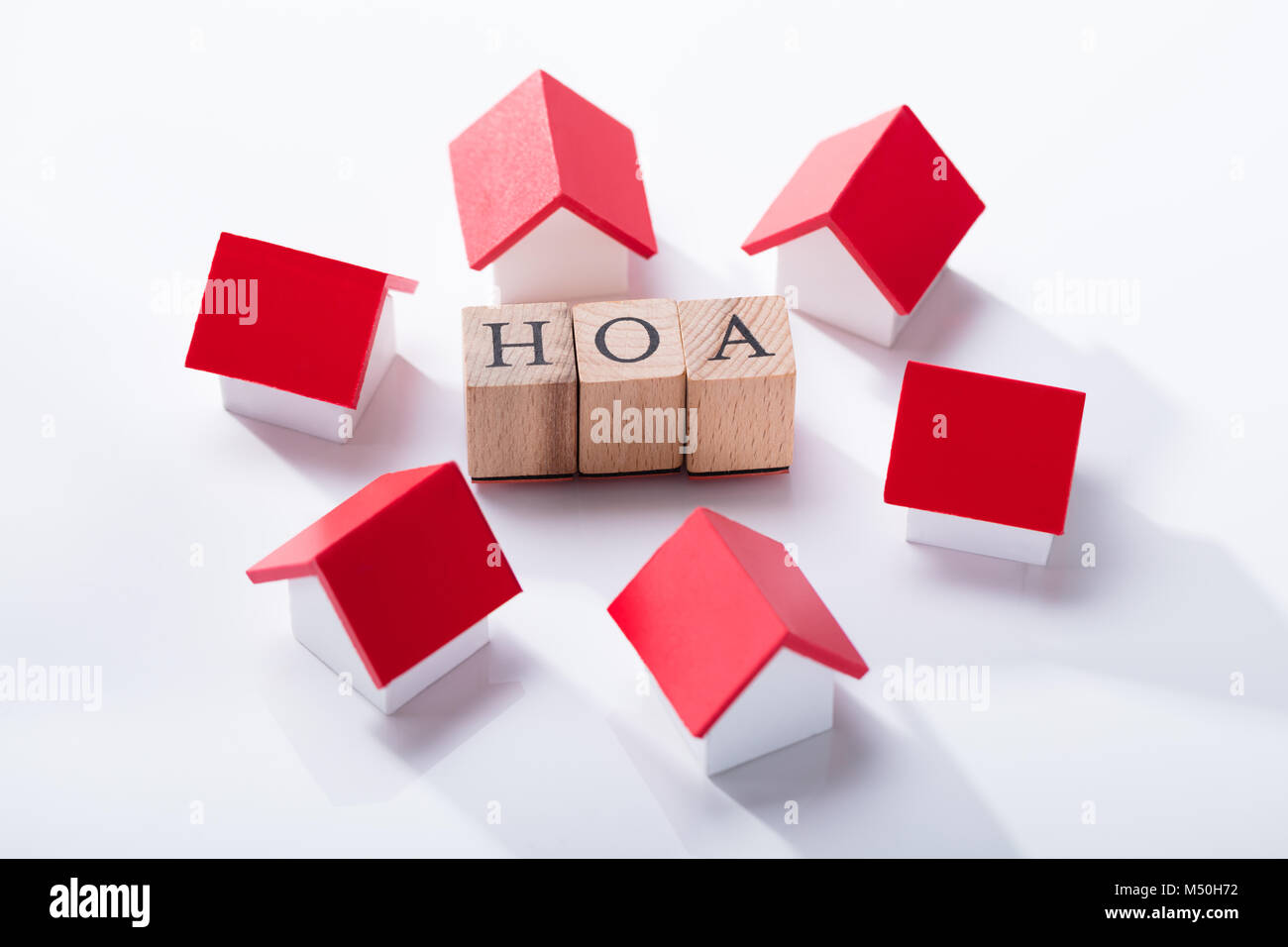 L'Association propriétaire des blocs en bois entourés de modèles de maison miniature sur le fond blanc Banque D'Images