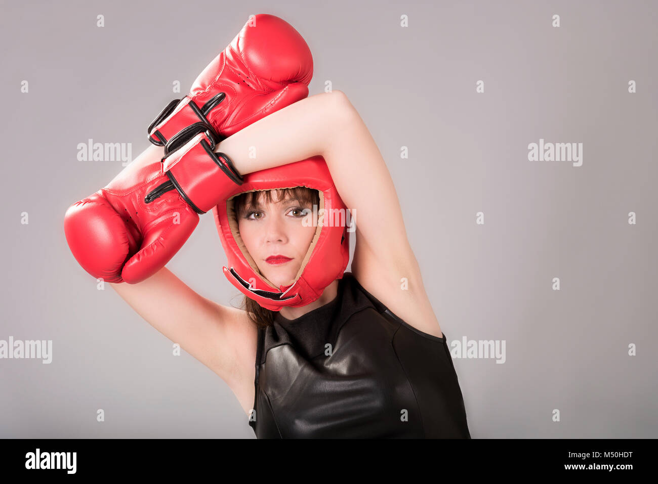 Femme portant un haut noir, des gants de boxe et un casque rouge Banque D'Images