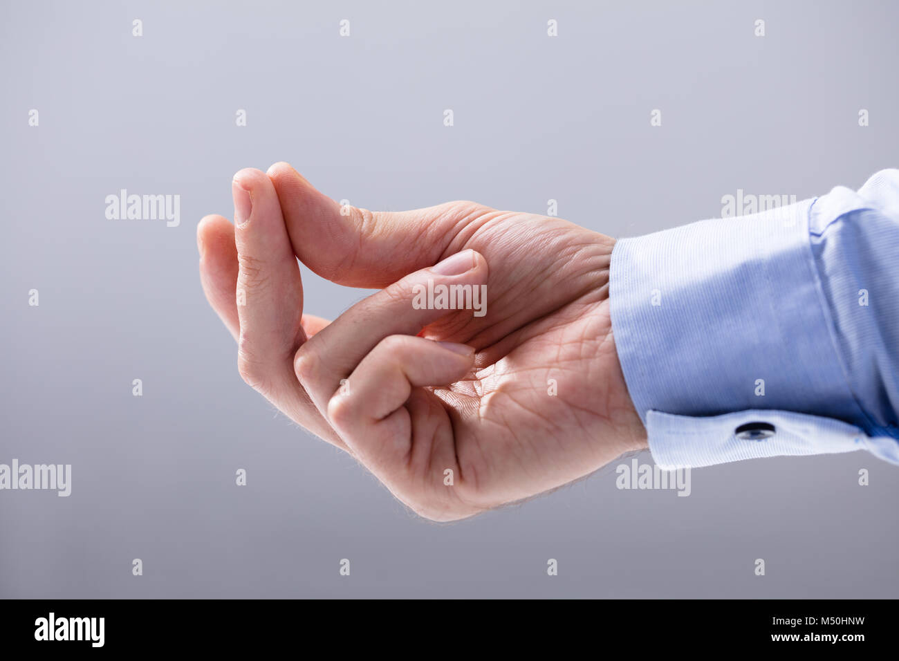 Close-up de la main de l'homme prendre son doigt contre fond blanc Banque D'Images