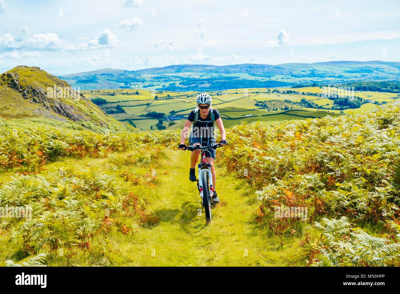 Vélo de montagne femelle sur le sentier longeant une grande Stickle au-dessus de la vallée de Duddon dans le Lake District Banque D'Images Vélo de montagne femelle sur le sentier longeant une grande Stickle au-dessus de la vallée de Duddon dans le Lake District Banque D'Images