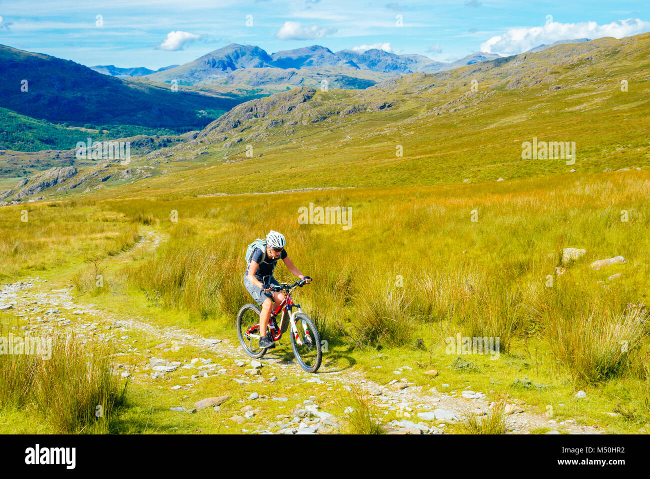 L'escalade vélo de montagne femelle Walna cicatrice au-dessus de la route dans la vallée de Duddon Lake District Banque D'Images