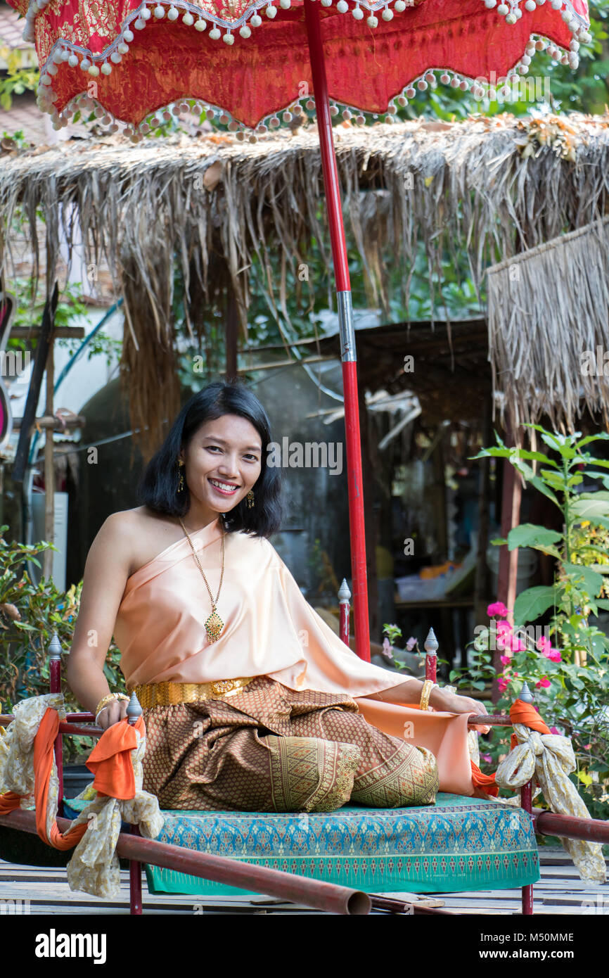 Jeune femme en vêtements traditionnels thaïlandais se trouve sur la portée historique. Thai girl dans le costume historique sous détendue parapluie. Banque D'Images