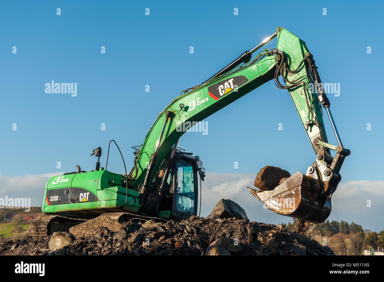 Excavatrice Caterpillar CAT 320D au travail déménagement terre/pierres avec ciel bleu et copie espace dans Skibbereen, comté de Cork, Irlande. Banque D'Images