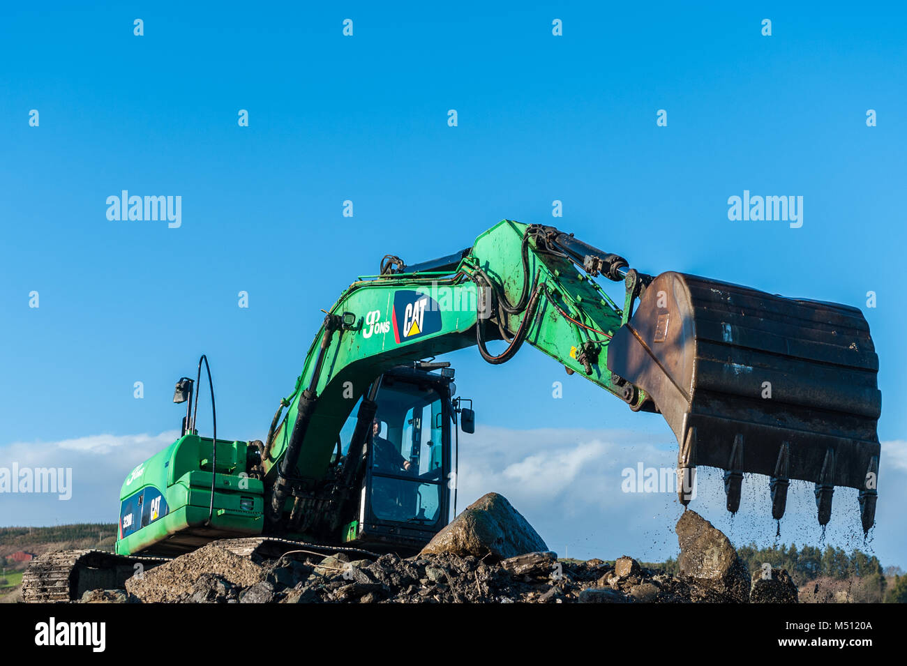 Excavatrice Caterpillar CAT 320D au travail déménagement terre/pierres avec ciel bleu et copie espace dans Skibbereen, comté de Cork, Irlande. Banque D'Images