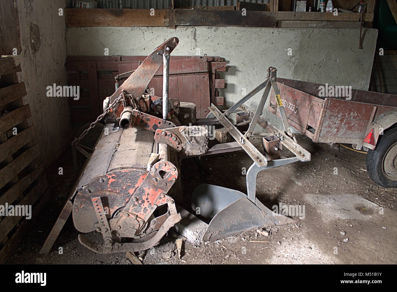 Old farm machinery gauche à l'arrière d'une grange à la rouille lentement. Banque D'Images