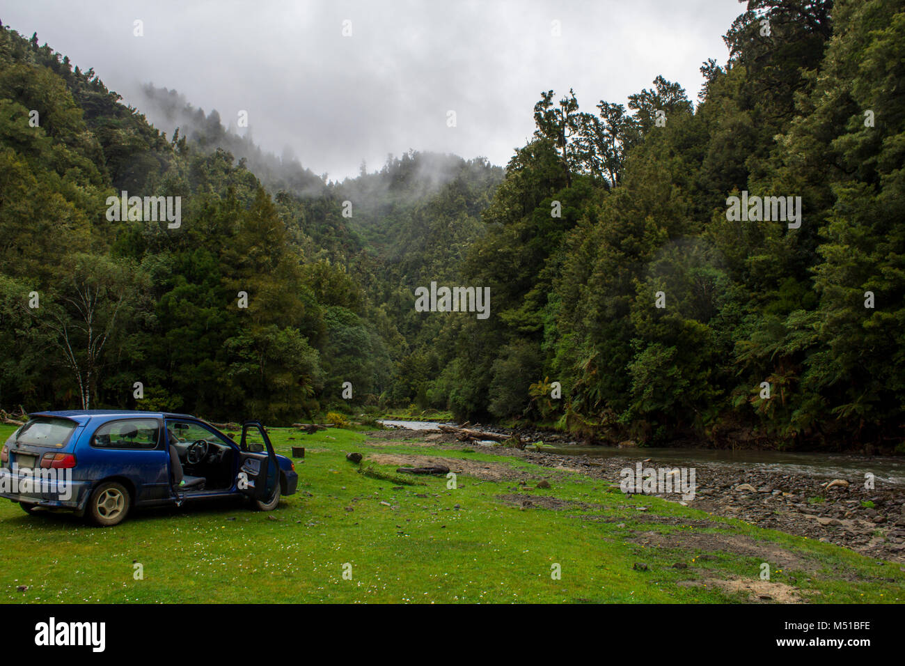 Voiture garée dans le paysage cinématographique, avec des montagnes, des forêts de brouillard et la rivière Banque D'Images