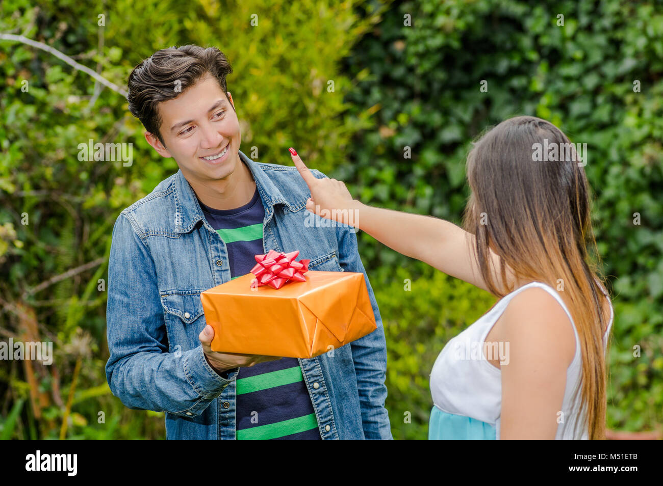 Close up of smiling man holding un cadeau et des fleurs et sa petite amie faisant un doigt pas signer, friend zone concept Banque D'Images