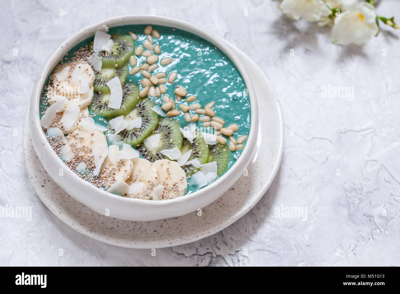 La spiruline petit-déjeuner smoothie coco bol garni de flocons de noix de coco et fruits rouges Banque D'Images