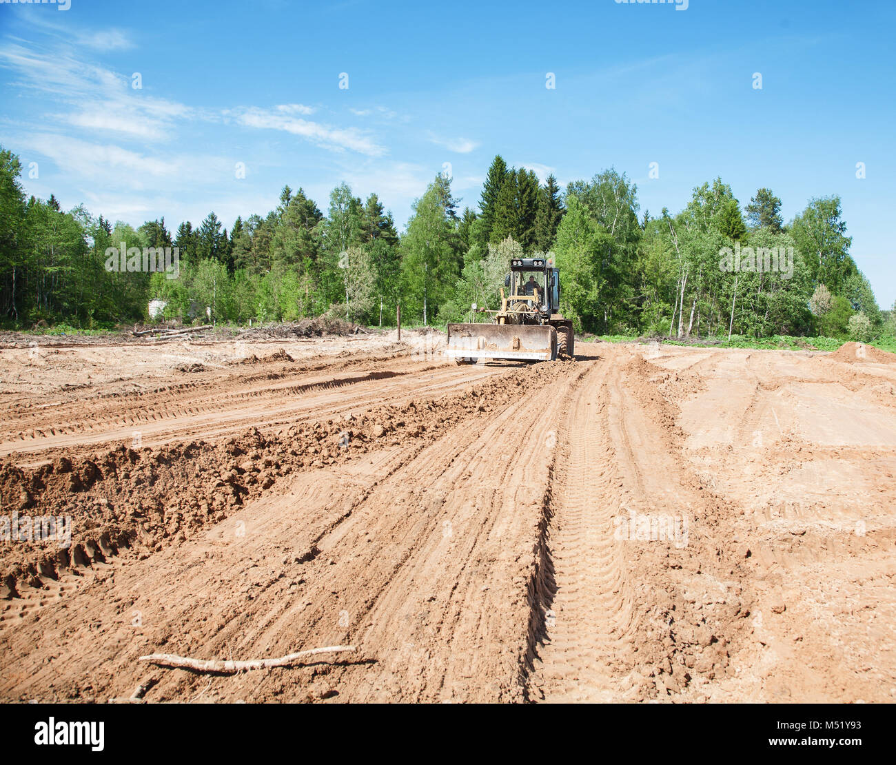 La niveleuse élimine un terrain dans l'après-midi Banque D'Images