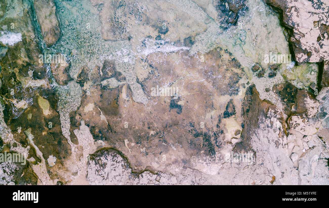 Vue aérienne de briser les vagues sur les rochers. Les vagues de la mer sur la magnifique plage de rochers colorés. Vue aérienne drone 4k shot. Zoom in Banque D'Images