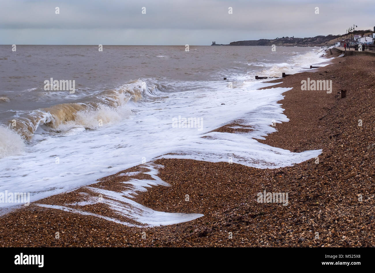 Mousse blanche surfez sur le rodage de la plage de galets sur une période d'orage jour d'hiver à Herne Bay, Kent, UK Banque D'Images
