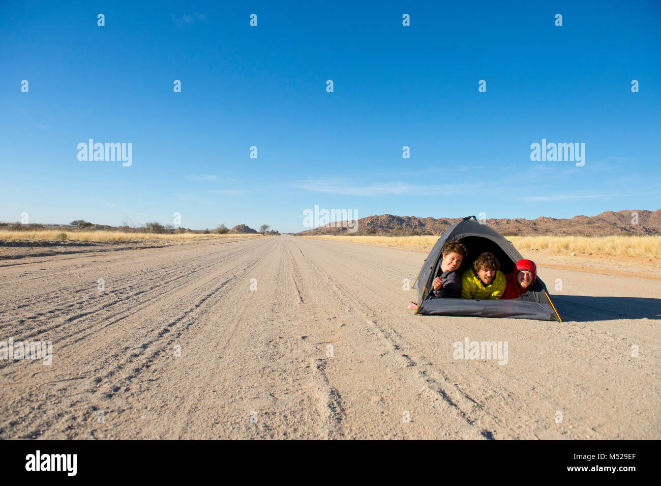 Trois personnes se trouvant dans la petite tente au milieu du chemin de terre dans la région de Savannah, Erongo, Namibie Banque D'Images