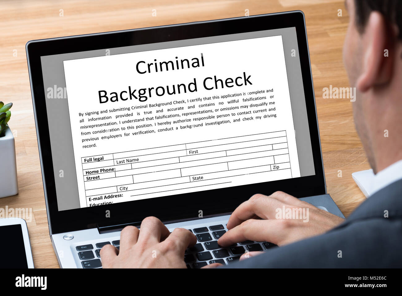 L'homme de remplir le formulaire de demande de vérification des antécédents criminels sur Laptop In Office Banque D'Images