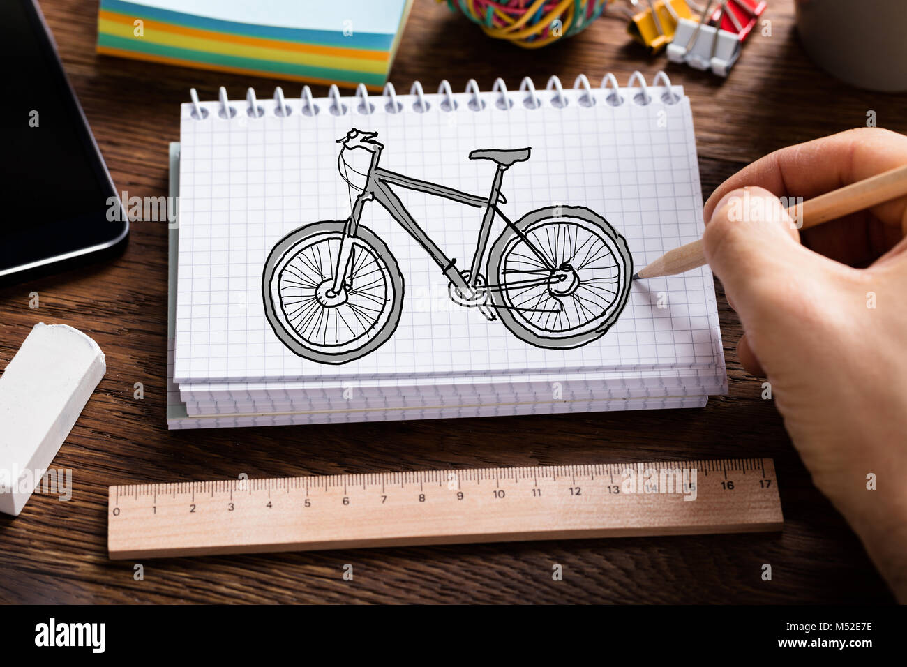 Close-up of Person's Hand Cycle Dessin Livre en spirale avec mètre et d'une gomme sur la table Banque D'Images