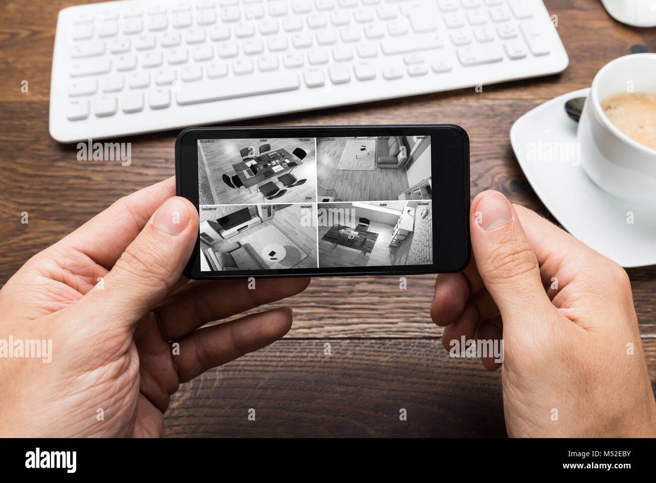 Person's Hand Holding Smartphone et la surveillance vidéo avec contre Table en bois Banque D'Images
