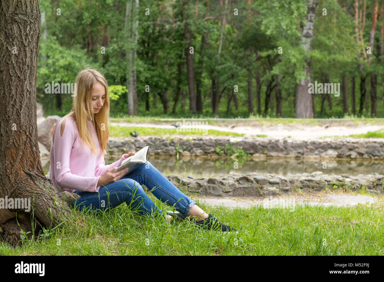 Cute young girl reading a book in the city park Banque D'Images