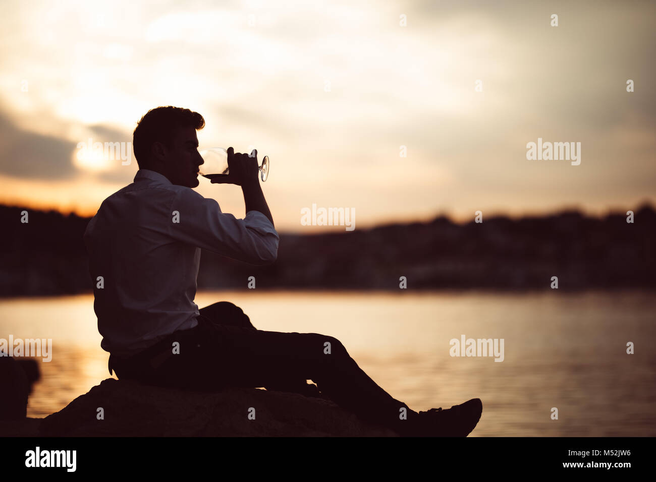 Les jeunes ont souligné business man drinking wine seul.Boissons homme mécontent de sa vie, dépendant de l'alcool.Binge drinking.Seul avec un verre à la main. Banque D'Images