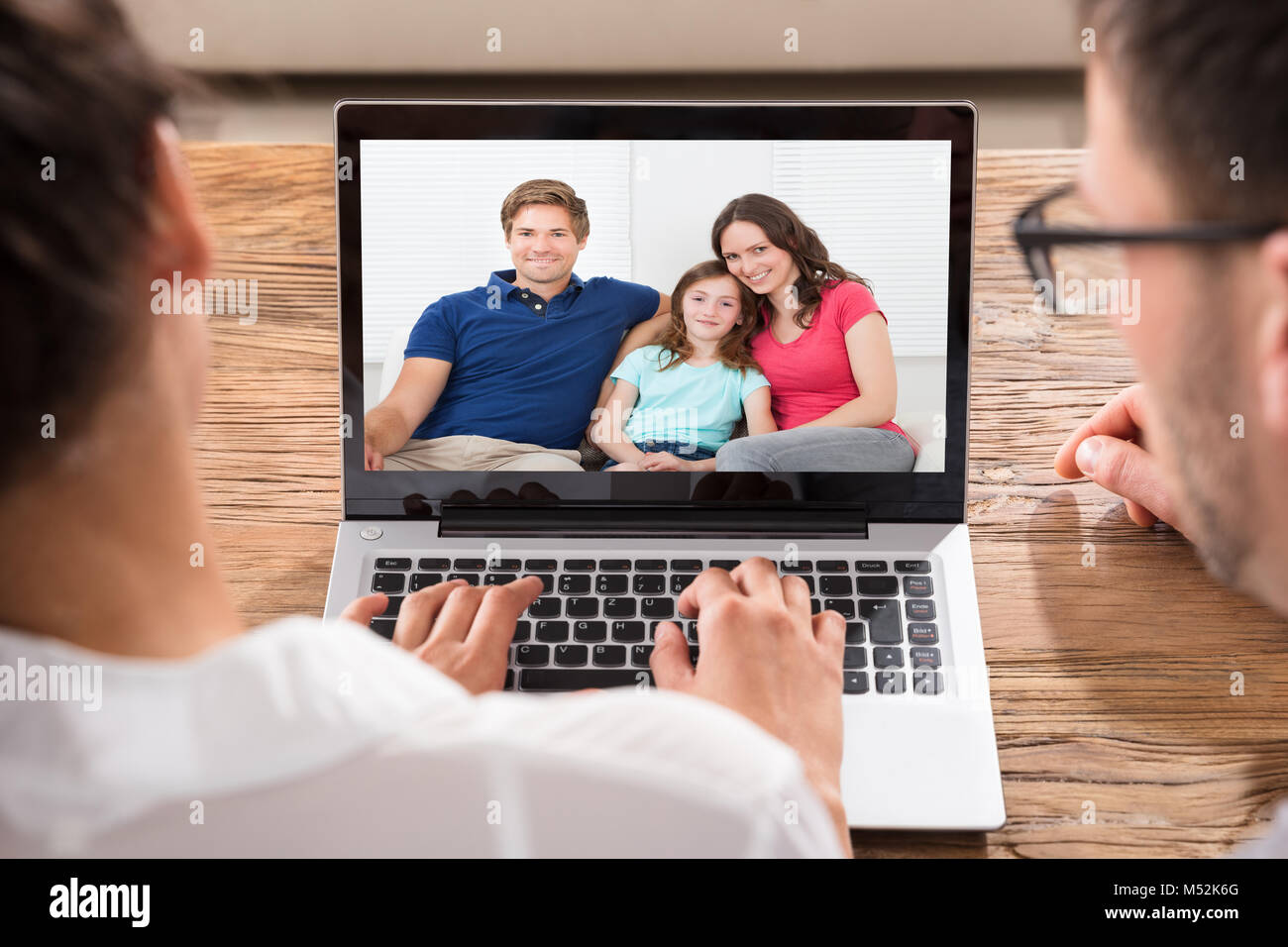 Close-up de deux personnes vidéo-conférence avec la famille sur Laptop At Desk Banque D'Images