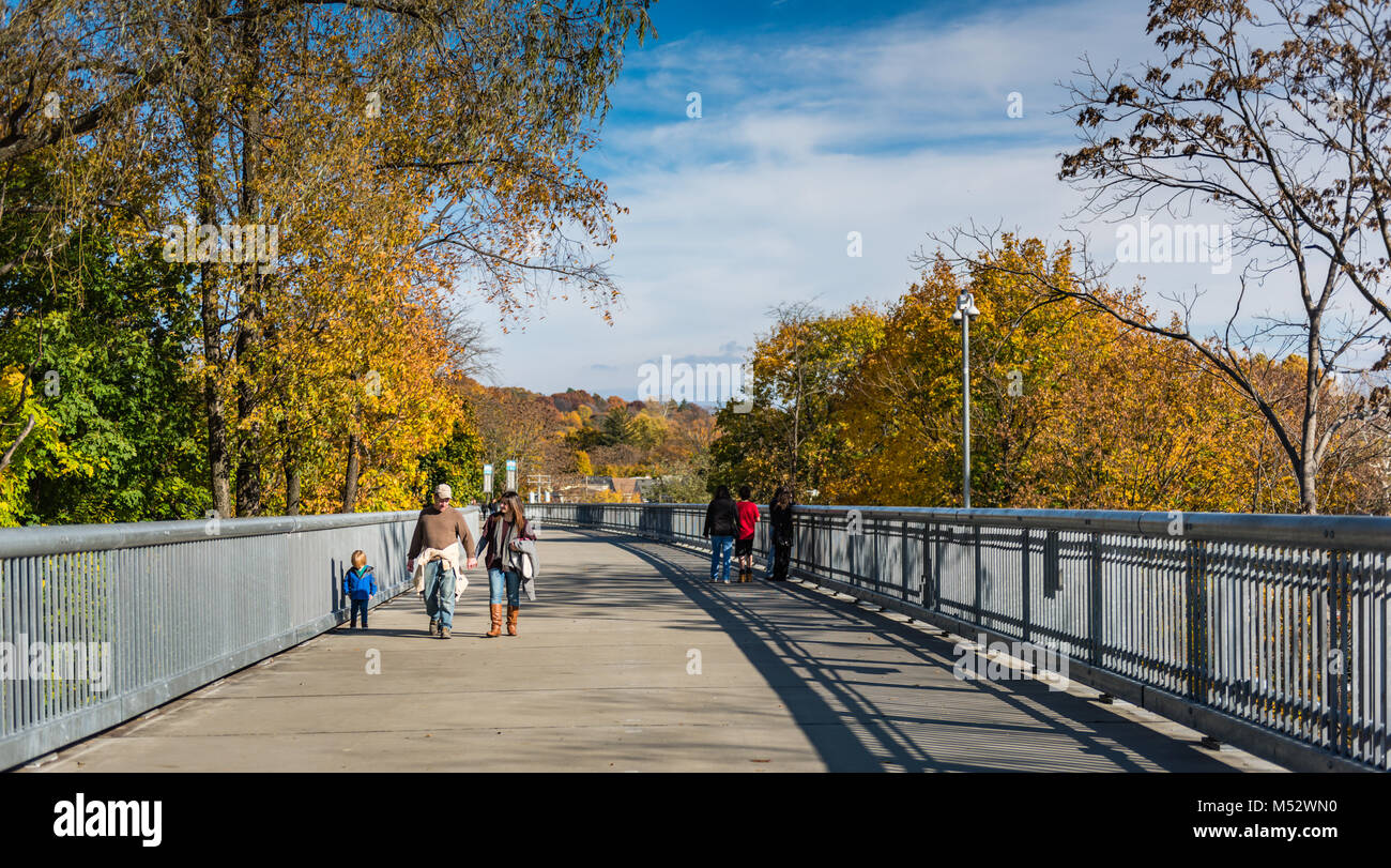 Encadré par l'orange et jaune feuilles de feuillage d'automne, une famille avec ayoung enfant marche le long de la promenade sur l'Hudson, un pont cantilever en acier Banque D'Images