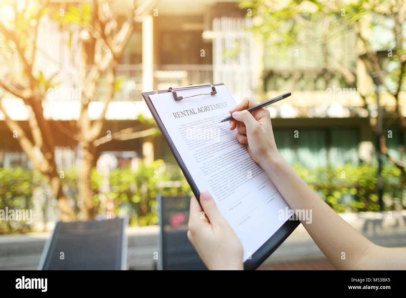 Close up of woman mains signature contrat de location journée ensoleillée retour condo. Utilisé avant avec Open Font License Banque D'Images