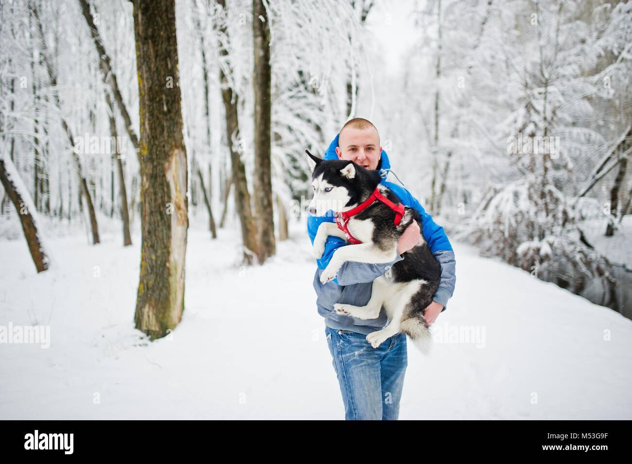 Homme avec chien husky au parc enneigé en hiver. Banque D'Images Homme avec chien husky au parc enneigé en hiver. Banque D'Images