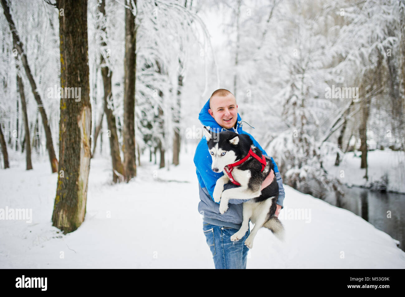 Homme avec chien husky au parc enneigé en hiver. Banque D'Images Homme avec chien husky au parc enneigé en hiver. Banque D'Images
